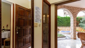 A hotel entrance with a wooden door, a sign about private accommodation regulations, and an outdoor patio area with a wicker chair and a small pool. - für zwei Personen by Interhome (Fažana)