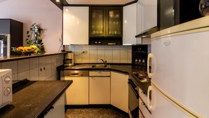 Una cocina compacta con armarios blancos, horno integrado y cafetera.