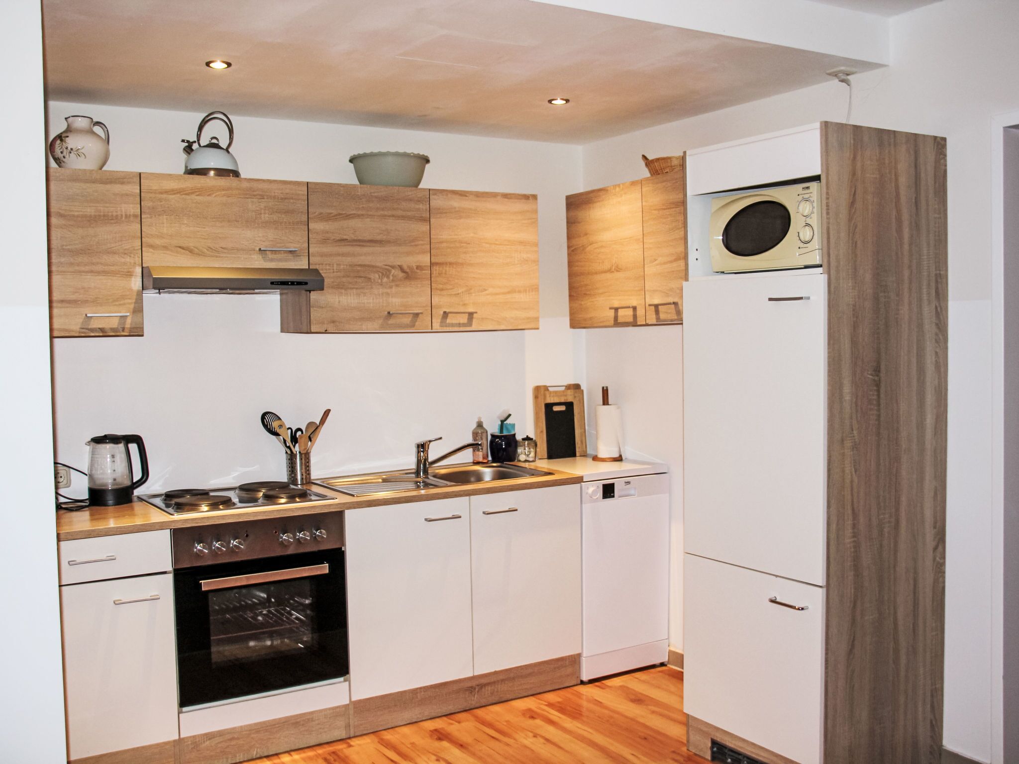 Una cocina compacta con gabinetes de madera, horno empotrado, microondas y lavavajillas.