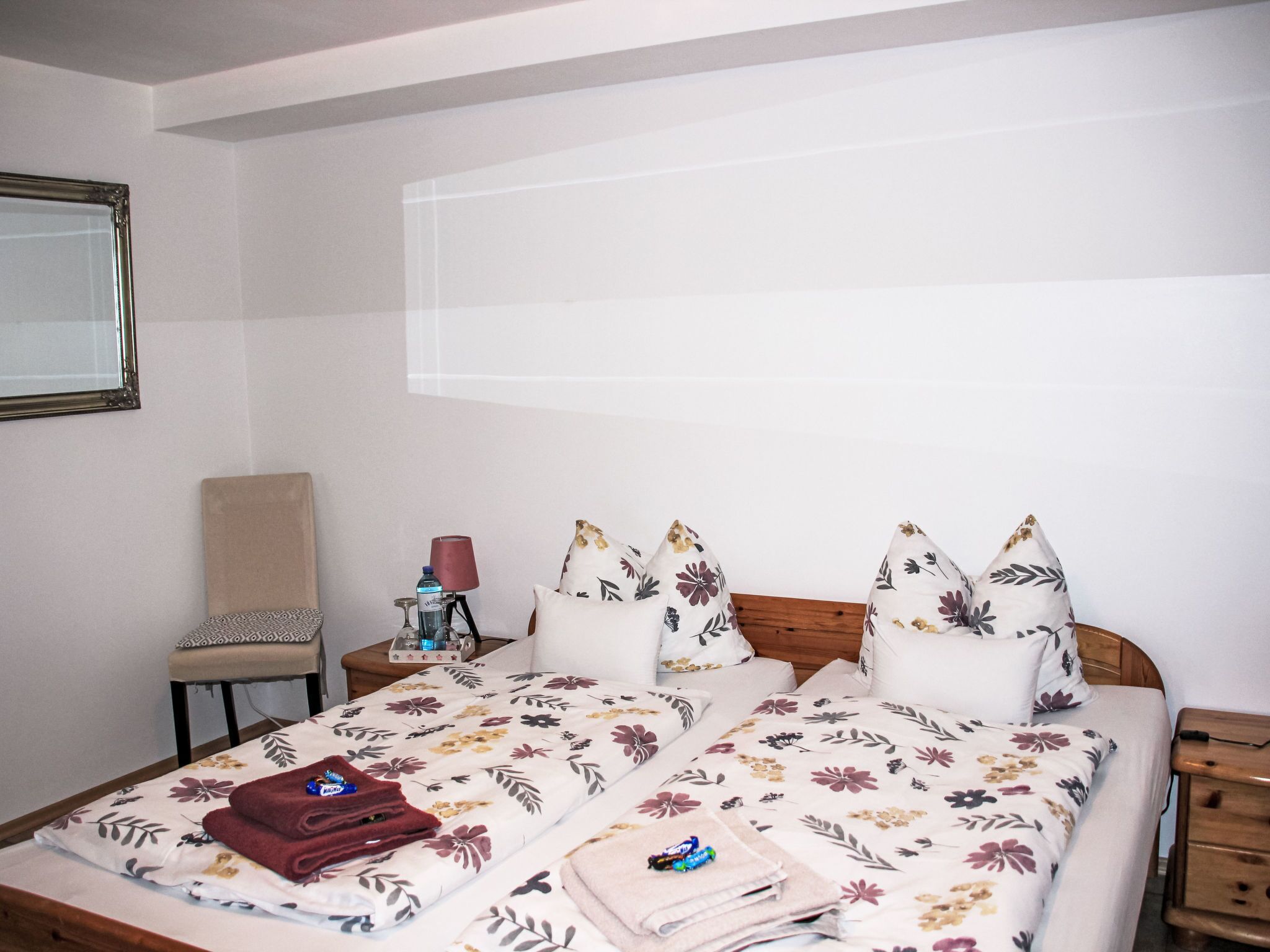 Una habitación de hotel con una cama, una silla, una mesita de noche y una mesita auxiliar.