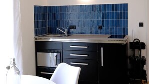 Eine moderne Küche mit blauer Wandfliesen, einem weißen Esstisch mit Stühlen und einer Kaffeemaschine.