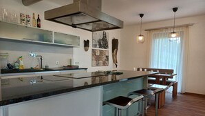 Una cocina moderna con una isla central, taburetes de bar y un comedor con una mesa y sillas de madera.