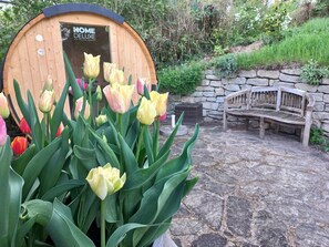 A wooden structure labeled "HOME DELUXE" surrounded by tulips and a stone bench.
