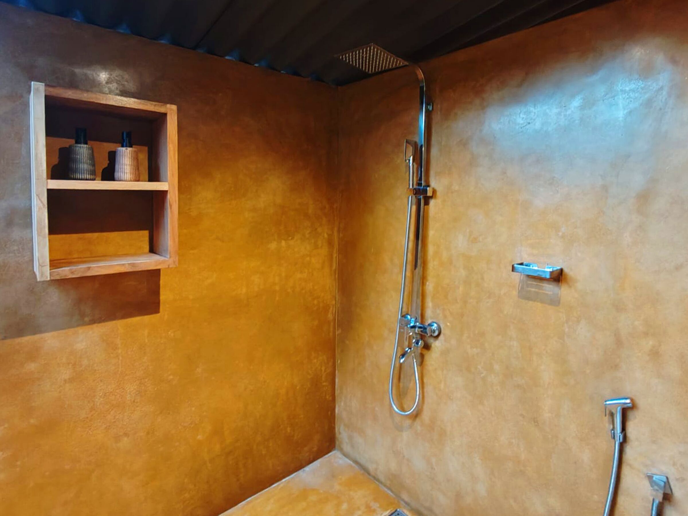 A shower with a handheld showerhead and a wall-mounted faucet.