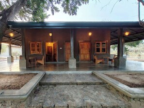 A covered outdoor area with a concrete floor, wooden benches, and a central door. - Yaalu Yaala Safari Camp (Palatupana)