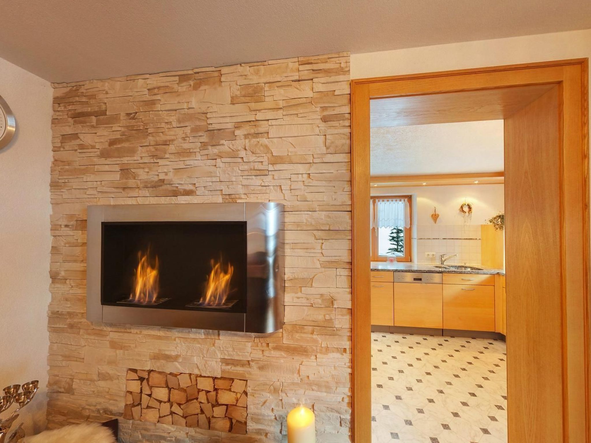 Una sala de estar moderna con una pared de piedra, chimenea y televisor integrado.