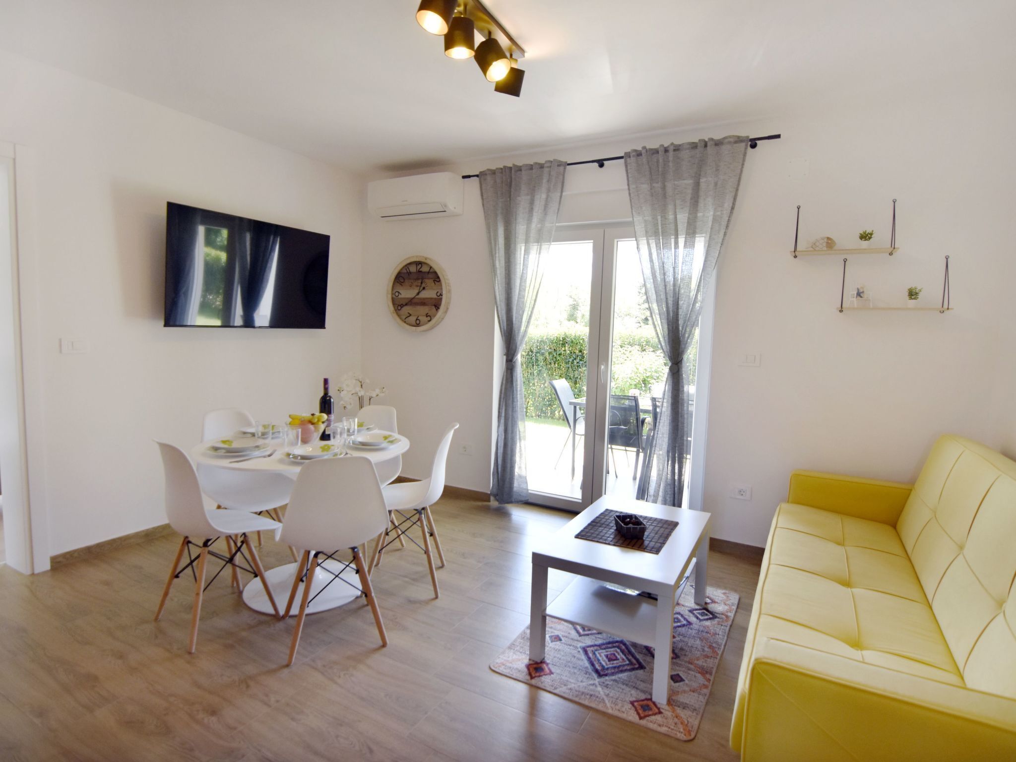 Een moderne woonkamer met een eethoek, met een bank, een tafel, stoelen en een televisie.