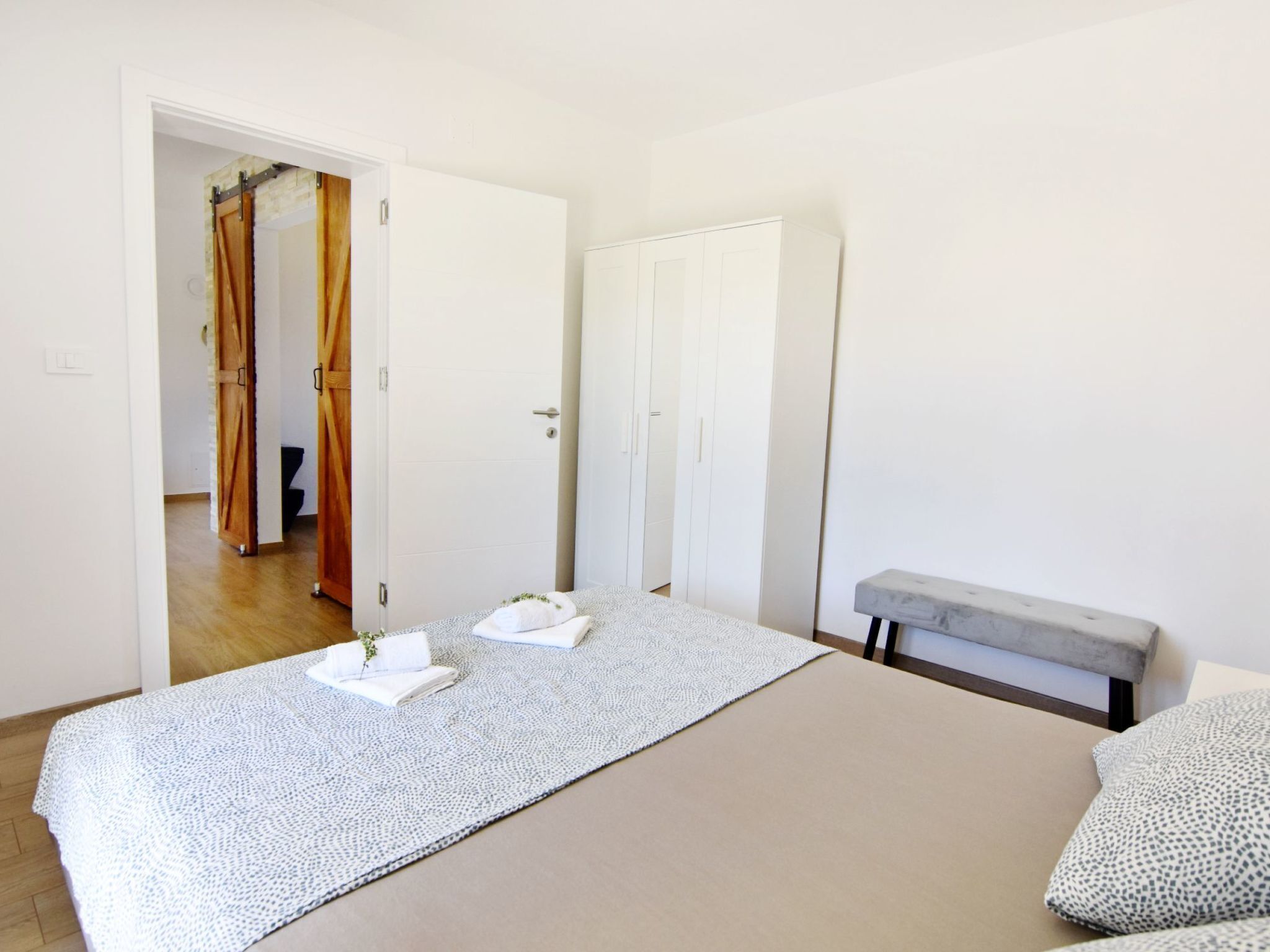 A bedroom with a bed, a bench, and a wardrobe.
