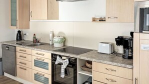 Uma cozinha moderna com armários de madeira, forno embutido, máquina de café e torradeira.
