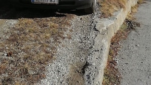 Un BMW plateado estacionado en un camino de grava con una casa al fondo.
