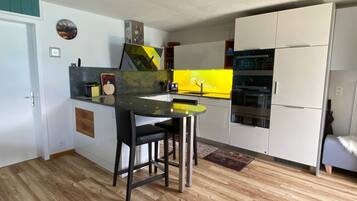 Une cuisine de taille réduite avec un îlot central, un réfrigérateur et un four à micro-ondes.