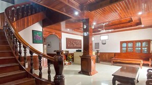 Una habitación amplia con una escalera de madera, una mesa grande de madera y un sofá.