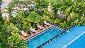 Una piscina en la azotea con sillones de descanso y abundante vegetación.