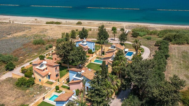 Un resort costero con villas, piscina y vistas a la playa.