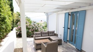 A covered patio area with a sectional sofa, a small table, and wicker chairs. - Vila Koko by Interhome (Opatija/Rukavac)
