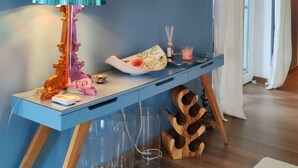 A room with a blue wall, a painting of a woman and child, a blue console table with a lamp, and a wooden shoe rack. - Vila Koko by Interhome (Opatija/Rukavac)