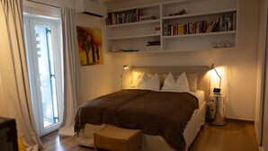 A bedroom with a large bed, bedside lamps, a bookshelf, and a painting on the wall. - Vila Koko by Interhome (Opatija/Rukavac)