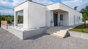 A modern two-story house with a flat roof, a satellite dish, and a small garden area. - Sunset Villa Santalezi by Interhome (Nedescina)