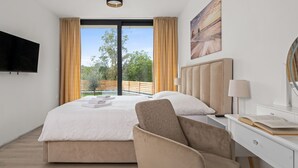 A modern hotel room with a large bed, a desk with a lamp, a chair, and a TV on the wall. - Sunset Villa Santalezi by Interhome (Nedescina)