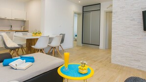 Una sala de estar moderna con un sofá, una mesita redonda con un florero, y un comedor con sillas y una mesa.