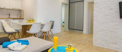 A modern living room with a sofa, a small round table with a vase, and a dining area with chairs and a table.