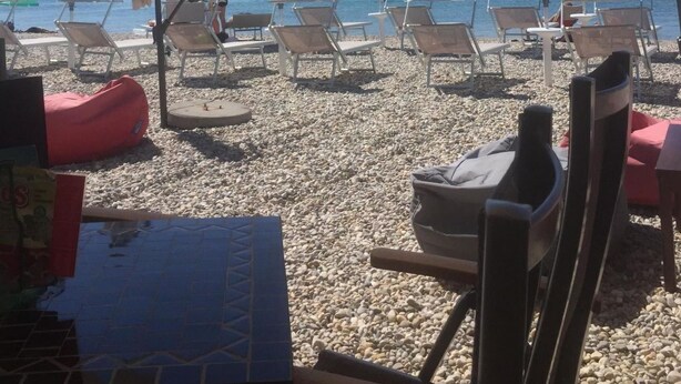 Een strand met zonneschermen en ligstoelen.