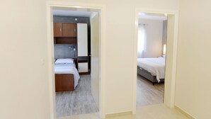 Een gang die leidt naar twee slaapkamers, elk met houten kasten en een bed.