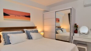 A bedroom with a bed, bedside table, dresser, and a painting of a sunset. - Wohnung Bruno - Luxuriöses Penthouse by Interhome (Zadar)