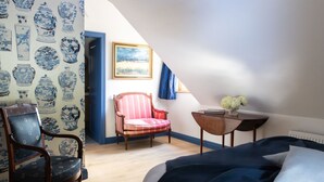 A bedroom with a bed, a chair, a small table, and a painting on the wall. - Chateau-Studio Bleu by Interhome (Marnand)
