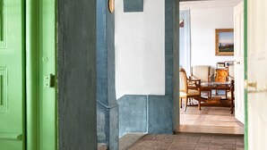 A room with a green door, a brick floor, and a dining area with chairs and a table. - Chateau-Studio Bleu by Interhome (Marnand)
