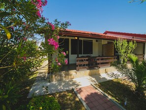 A building with a red-tiled roof, a covered outdoor seating area, and a paved pathway leading to the entrance. - Gelassenheit am Meer 1 by Interhome (Nin)