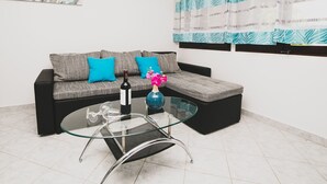 Un saló modern amb un sofà modular, una taula de centre de vidre i un vas decoratiu.