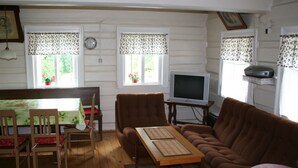 A cozy living room with a wooden table, chairs, a brown sofa, and a television. - Charmantes, traditionelles Holzhaus by Interhome (Jilemnice)