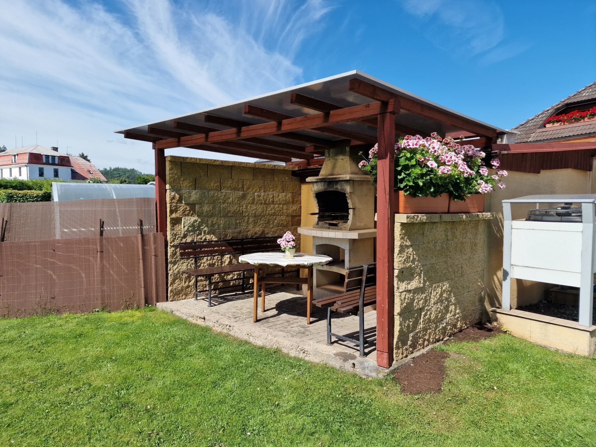 Eine Terrasse im Freien mit einem Steingrill, einem Holztisch und Stühlen.