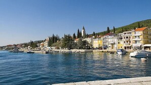 Un pueblo costero con un puerto deportivo, edificios históricos y una imponente torre de iglesia.