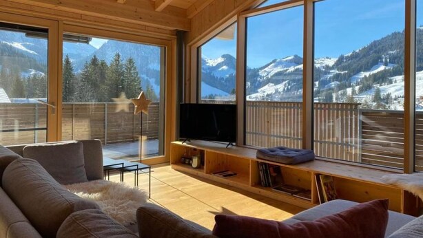 Ein gemütliches Wohnzimmer mit einem großen Fenster mit Blick auf eine verschneite Berglandschaft.