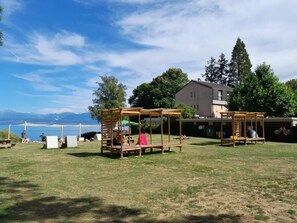 An outdoor area with wooden structures, a grassy field, and a building in the background. - in Bauernhof by Interhome (Luins)