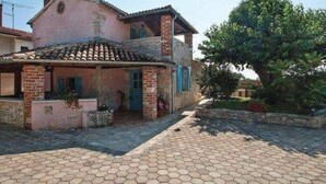 Une maison à deux étages, avec un toit en tuiles et des murs en briques, un porche couvert et une allée pavée.