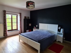 Ein Schlafzimmer mit Bett, Nachttischen, einem Kleiderschrank und einem Fenster mit Vorhängen.