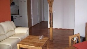A living room with a wooden coffee table, a sofa, and a wooden chair. A kitchen is visible in the background. - Zu den drei Schönen by Interhome (Boitzenburger Land)