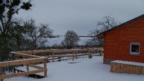 A wooden cabin with a snow-covered ground and a wooden fence. - Zu den drei Schönen by Interhome (Boitzenburger Land)