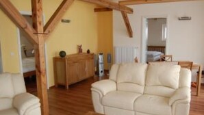 Un soggiorno ampio con soffitto in legno, un divano beige e un mobiletto in legno.