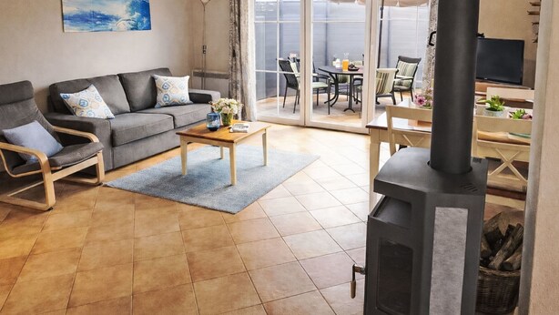 Een woonkamer met een bank, fauteuils, een salontafel, een open haard en een schuifpui die leidt naar een terras.
