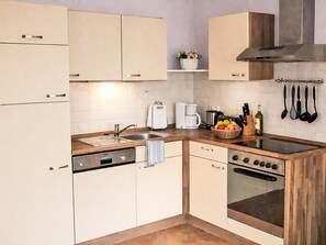 A modern kitchen with a dishwasher, oven, and coffee maker. - in Pruchten mit Sauna und Kamin by Interhome (Bodstedt)