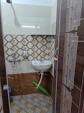 A bathroom with a white sink, a shower, and patterned tiles. - Laxmi Nrusingha Bhawan (Puri)