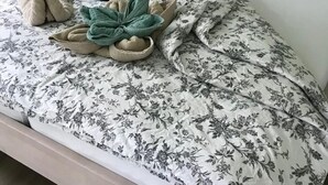 A neatly made bed with floral bedding, a green throw blanket, and a small stuffed animal. - Zochiserlebnishof by Interhome (Burg (Spreewald))