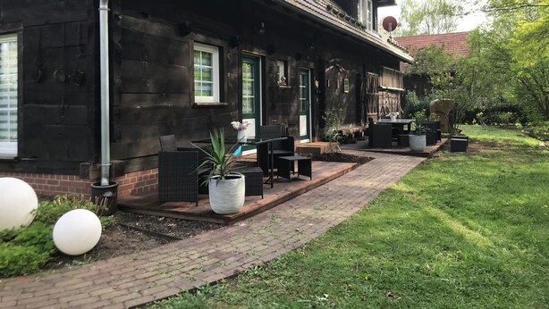 A wooden house with a covered patio, outdoor seating, and a garden with spherical decorations. - Zochiserlebnishof by Interhome (Burg (Spreewald))
