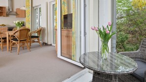 En modern lägenhet med matplats, kök och en balkong med ett glasbord och stolar.