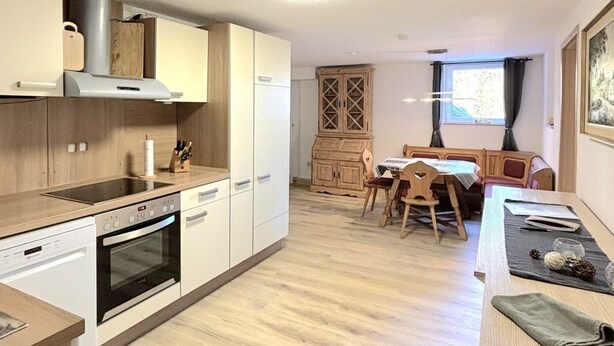 Eine moderne Küche mit Holzschränken, einem eingebauten Ofen und einem Essbereich mit einem Holztisch und Stühlen.