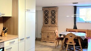 Eine moderne Küche mit weißen Schränken, einem Holzschrank und einem Essbereich mit Tisch und Stühlen.